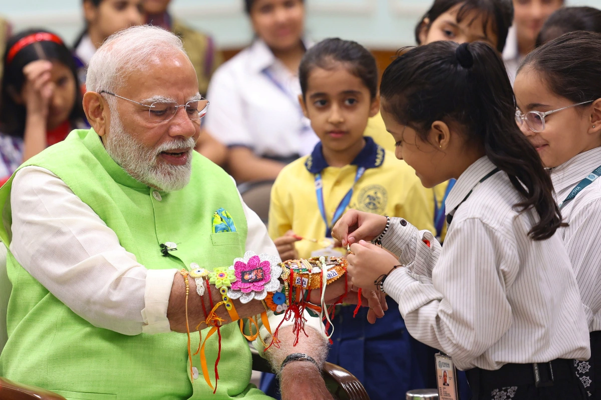 Caption: New Delhi: School students tie ‘rakhi’ onto the wrist of Prime Minister Narendra Modi on the occasion of Raksha Bandhan in New Delhi on Monday, August 19, 2024.(Photo: IANS)