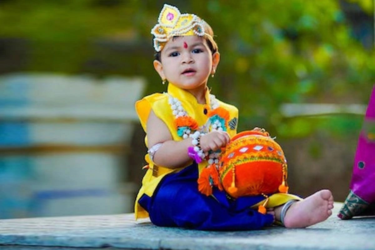 राजकुमार स्टाइल जिसमें आप बच्चे को नीली या सफेद रंग की रेशमी धोती या कुर्ता सेट पहना सकते हैं, साथ में मोर पंख वाला मुकुट और मोतियों की माला जो एकदम परफेक्ट और शानदार लगेगा.