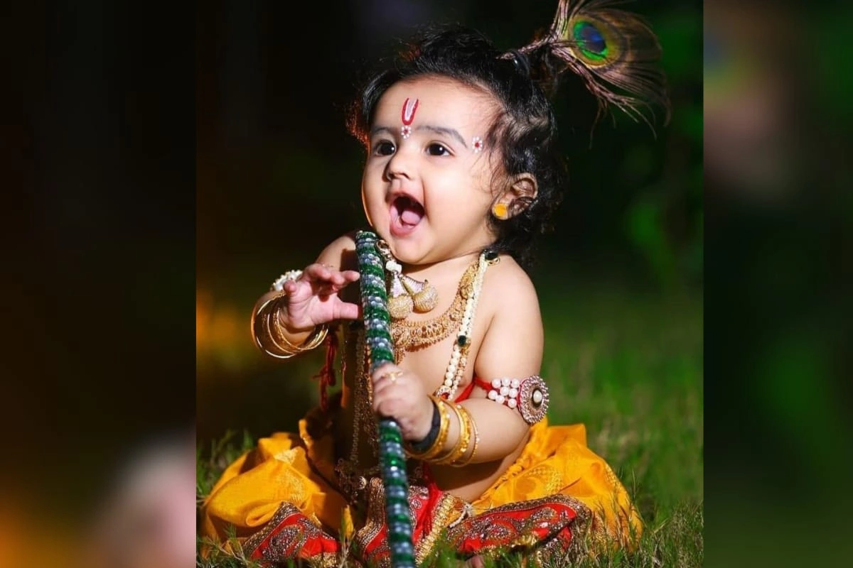 सबसे सरल और सुंदर, क्लासिक पीली धोती और मोर मुकुट लुक. ये लुक बेहद ही प्यारा और ट्रेडिशनल है जिसमें पीली धोती, मोर पंख वाला मुकुट, मोतियों की माला, कमरबंद, हाथ में बांसुरी, और अगर चाहे तो हल्का सा मेकअप भी कर सकते हैं.